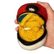 Dragonite reversible crochet pattern — a real photo of the unzipped ball with Dragonite inside, held in a hand