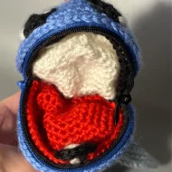 Poliwag reversible crochet pattern — a real photo of the unzipped ball with Poliwag inside, held in a hand