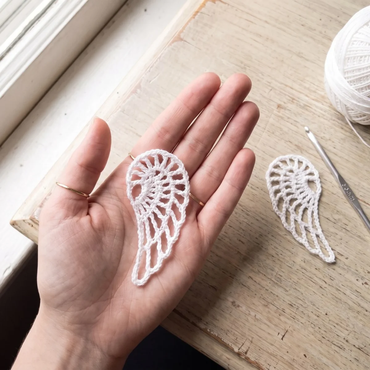 Openwork lace wings from the crochet angel ornament pattern held in a hand