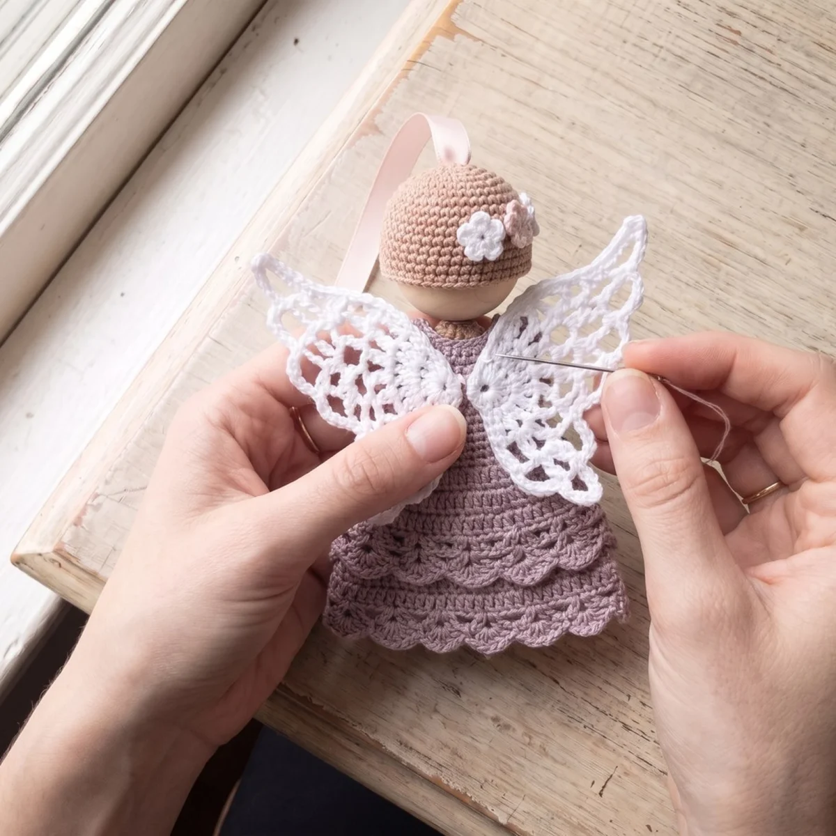 Sewing the lace wings on while making the crochet angel ornament pattern