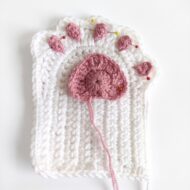 The dusty-rose paw pad and five toe pads sewn onto the glove, from the crochet cat paw gloves pattern