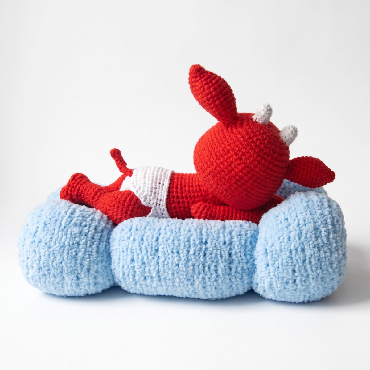 Side view of the crochet devil pattern showing the curled tail, the horns and the three rolls of the cloud