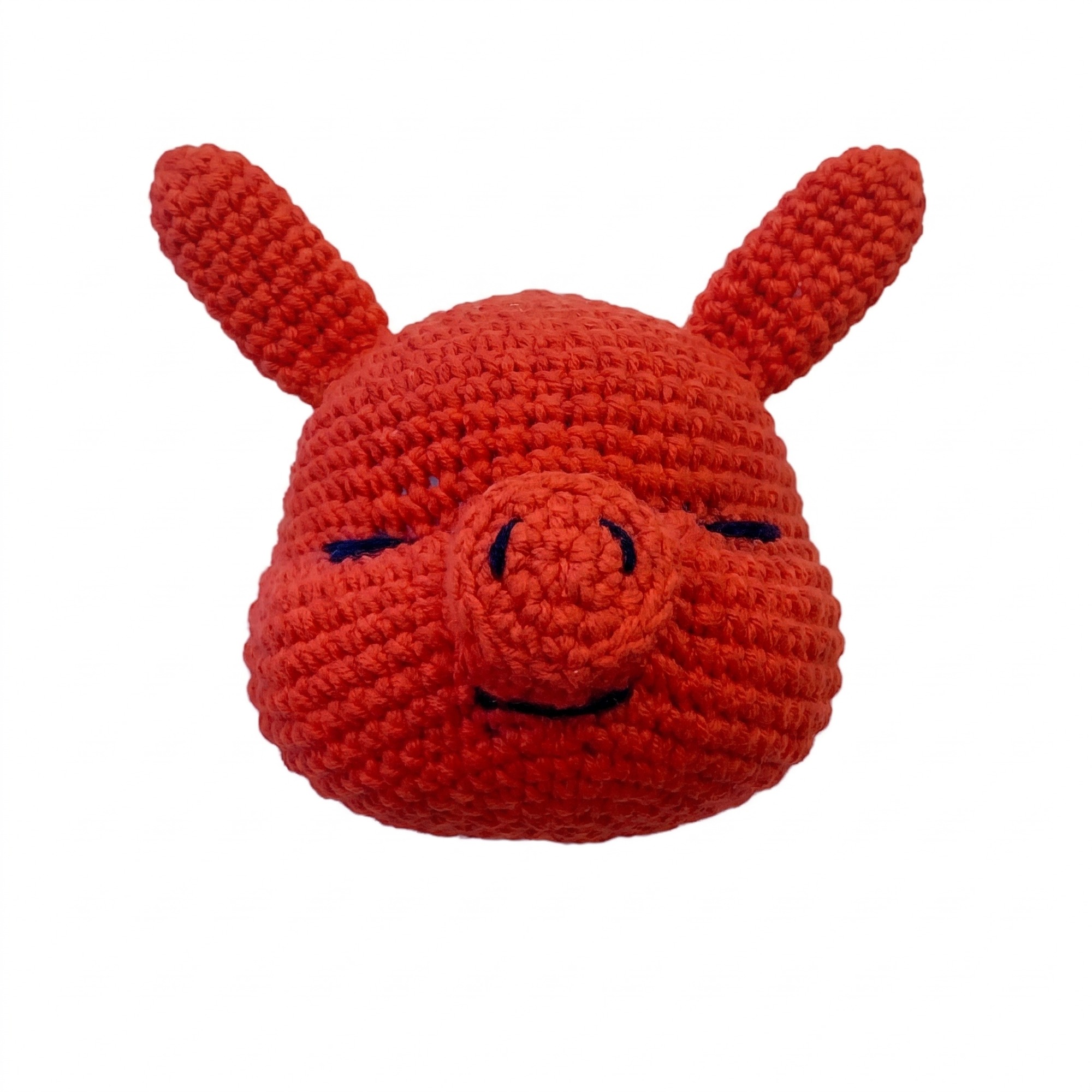 The embroidered closed eyes, raised snout and smiling mouth of the crochet devil pattern