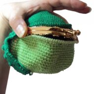 Fitting the gold metal frame into the lip of the crochet frog purse pattern