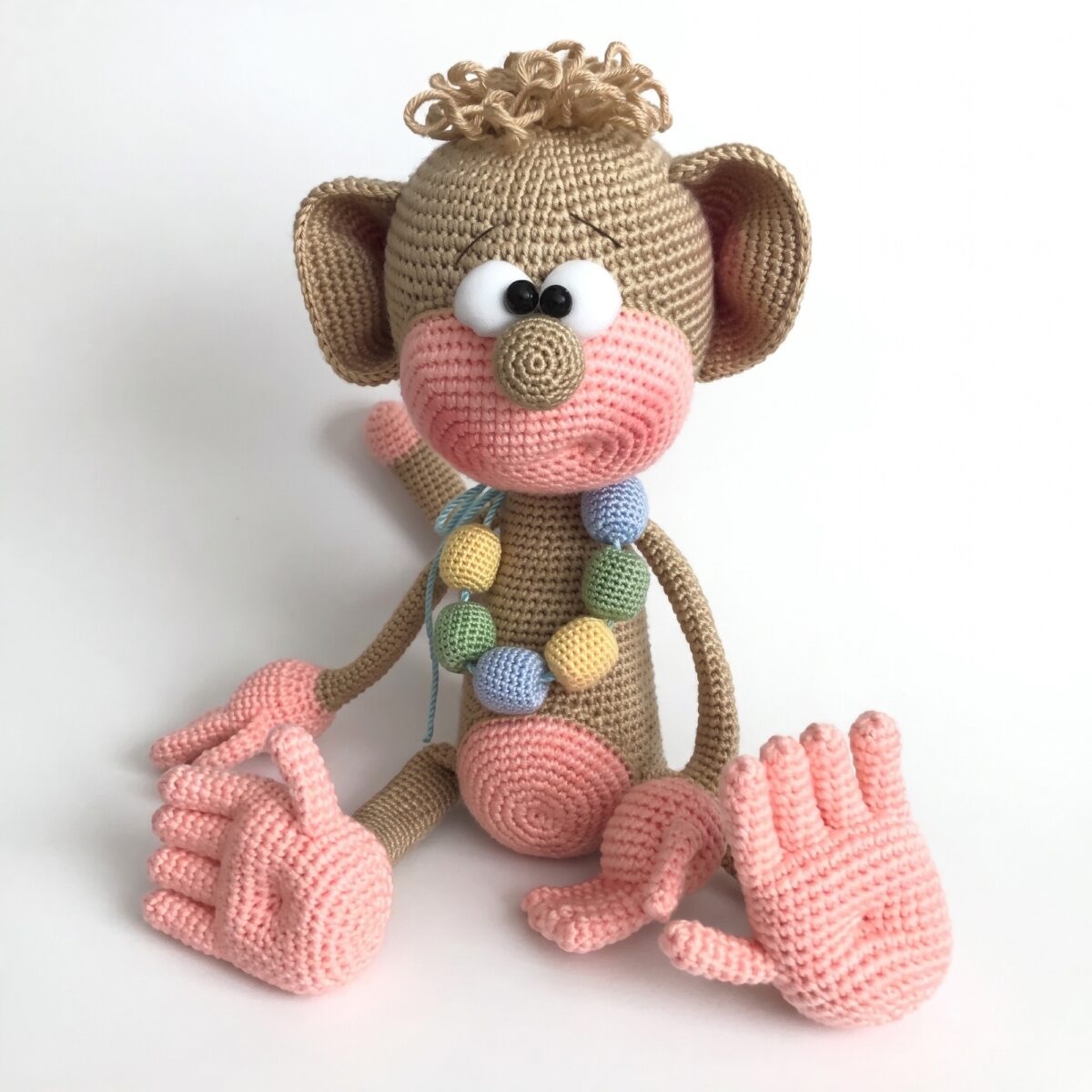 Crochet monkey pattern — the finished monkey The finished crochet monkey pattern — a caramel amigurumi monkey with a pink muzzle, five separate fingers and a crocheted bead necklace
