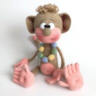 The finished crochet monkey pattern — a caramel amigurumi monkey with a pink muzzle, five separate fingers and a crocheted bead necklace