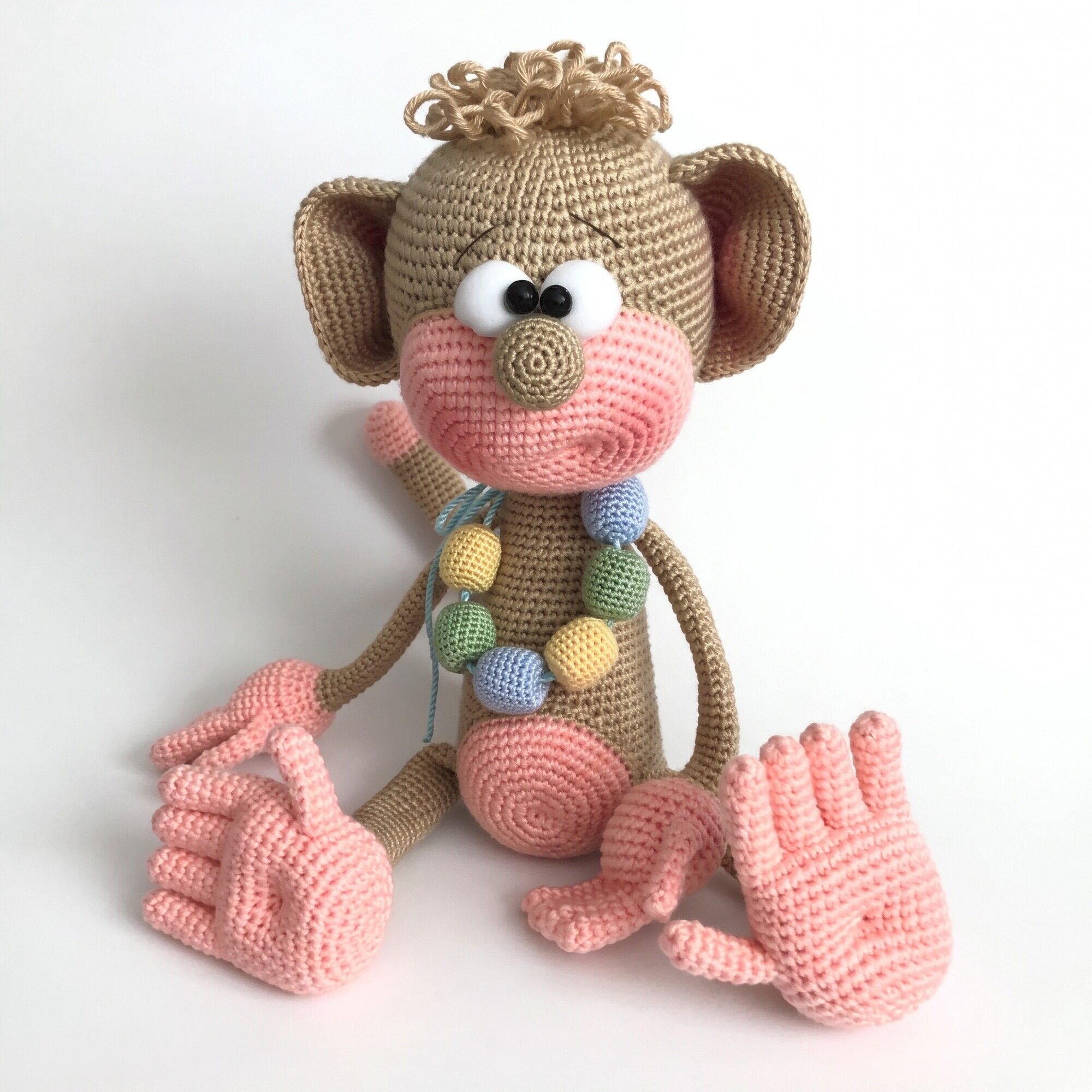 Crochet monkey pattern — the finished monkey The finished crochet monkey pattern — a caramel amigurumi monkey with a pink muzzle, five separate fingers and a crocheted bead necklace